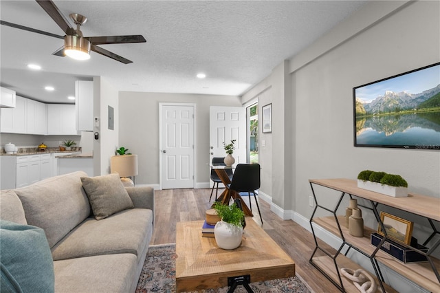 living area with recessed lighting, baseboards, a textured ceiling, and light wood finished floors