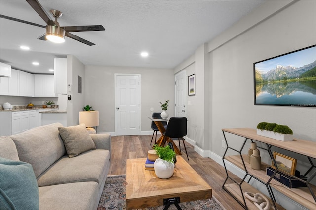 living area featuring a ceiling fan, baseboards, wood finished floors, and recessed lighting