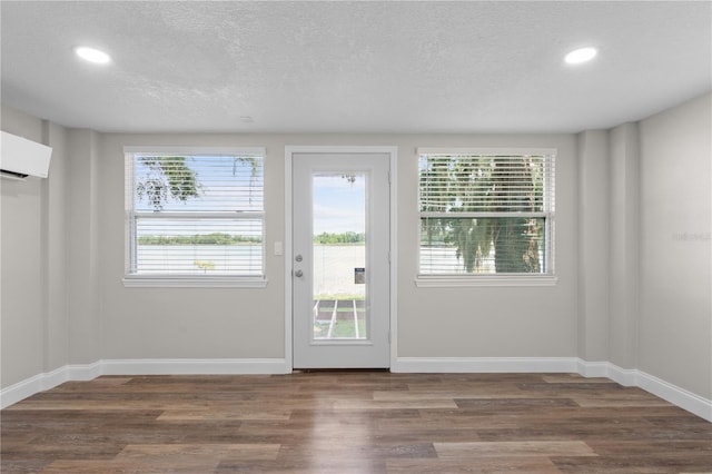 doorway with recessed lighting, a textured ceiling, baseboards, and wood finished floors