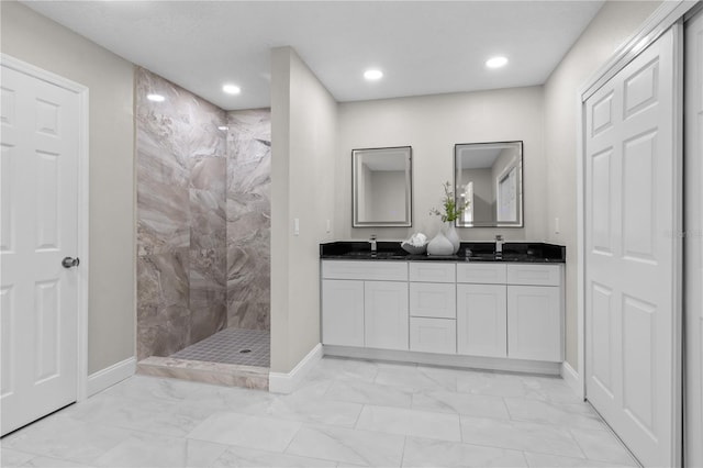 bathroom with marble finish floor, double vanity, baseboards, and walk in shower