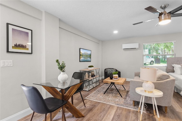 interior space featuring ceiling fan, a textured ceiling, wood finished floors, and a wall mounted AC