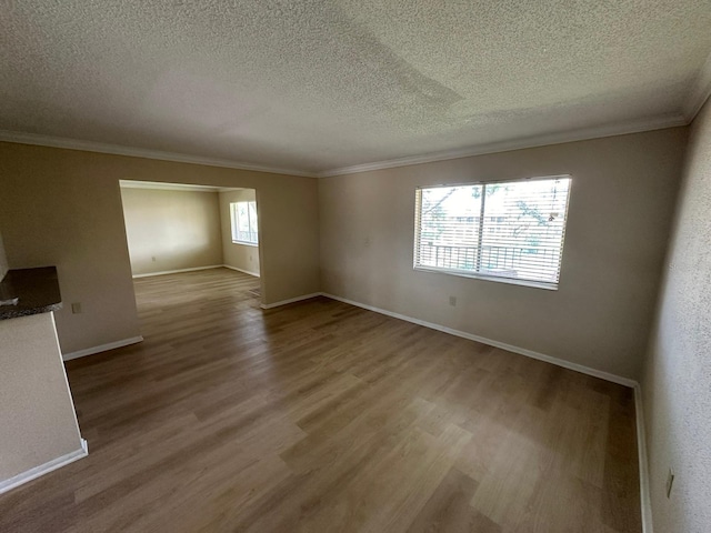 unfurnished room featuring wood-type flooring, a textured ceiling, and ornamental molding