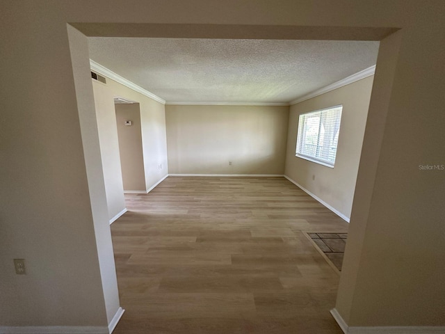 empty room with a textured ceiling, light hardwood / wood-style floors, and ornamental molding