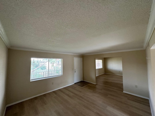 empty room with a healthy amount of sunlight, wood-type flooring, and ornamental molding