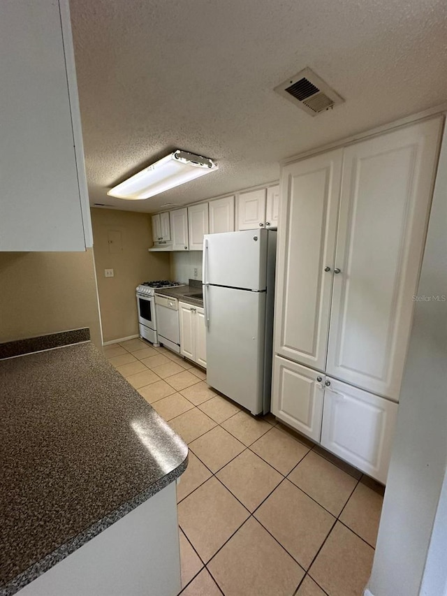 kitchen featuring light tile patterned floors, white appliances, a textured ceiling, and white cabinetry