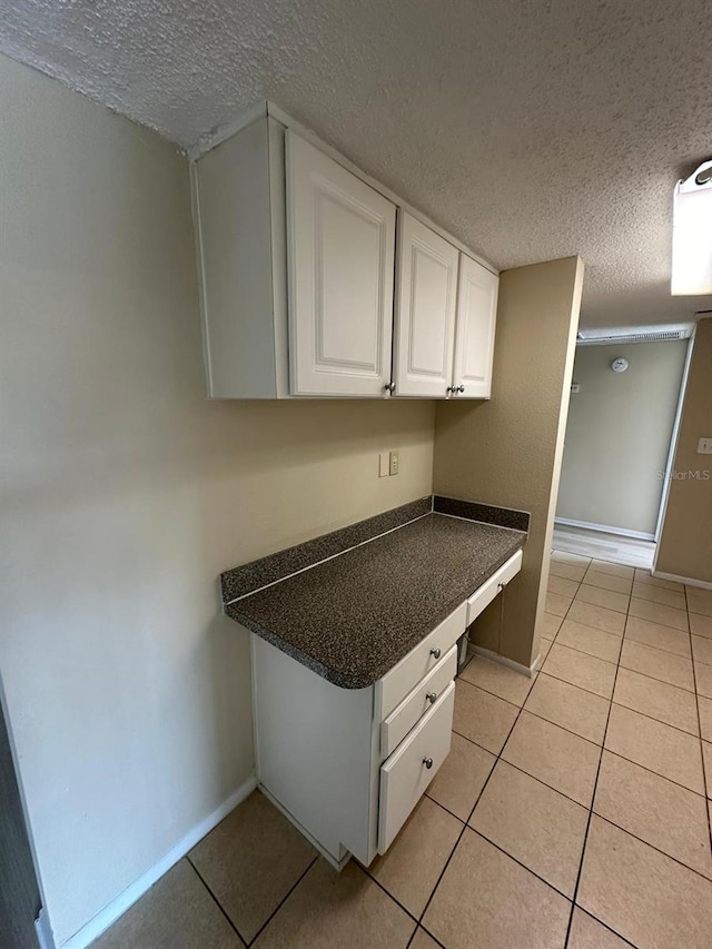 kitchen featuring white cabinets, light tile patterned floors, and a textured ceiling