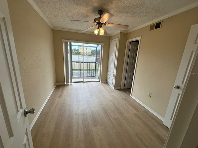 unfurnished room featuring ceiling fan, ornamental molding, a textured ceiling, and light wood-type flooring