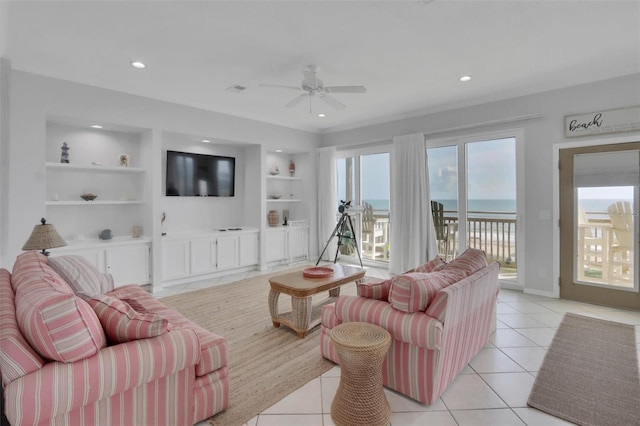 living room featuring a water view, ceiling fan, light tile floors, and built in features