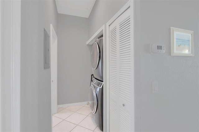 laundry area with light tile floors and stacked washing maching and dryer