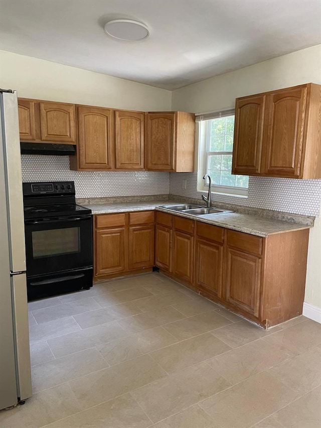 kitchen featuring black range with electric stovetop, fridge, sink, tasteful backsplash, and light tile floors