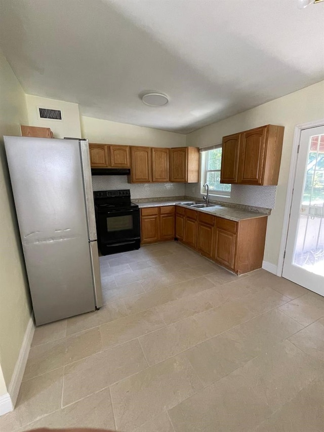 kitchen featuring sink, black range with electric stovetop, a wealth of natural light, and white fridge