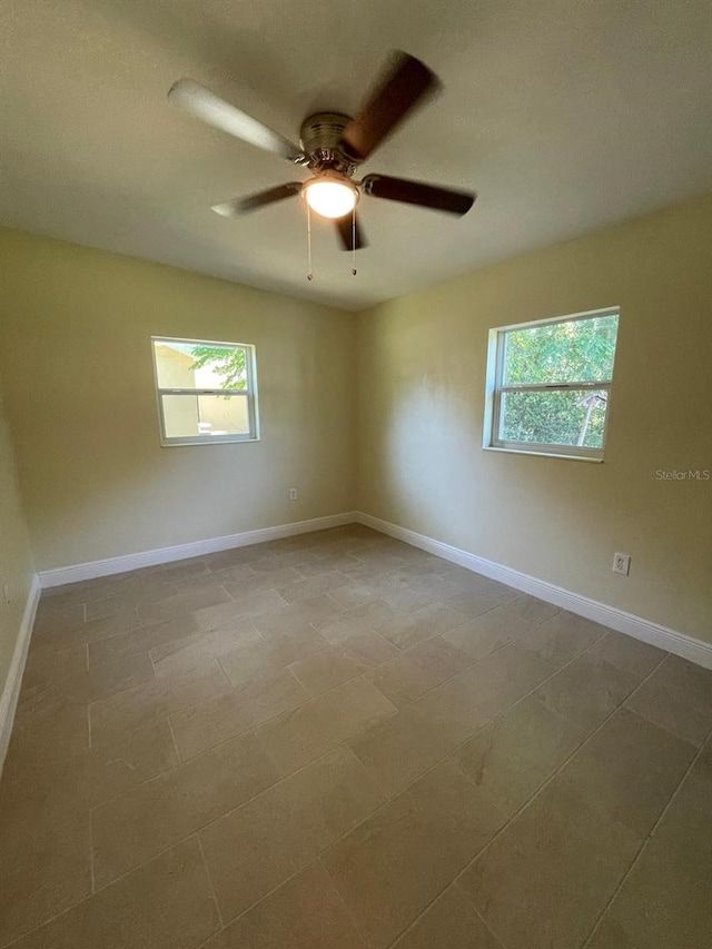 tiled spare room featuring a wealth of natural light and ceiling fan