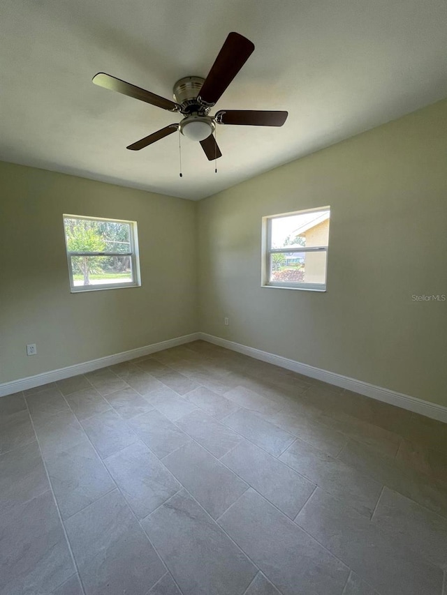 empty room with a healthy amount of sunlight, ceiling fan, and tile floors