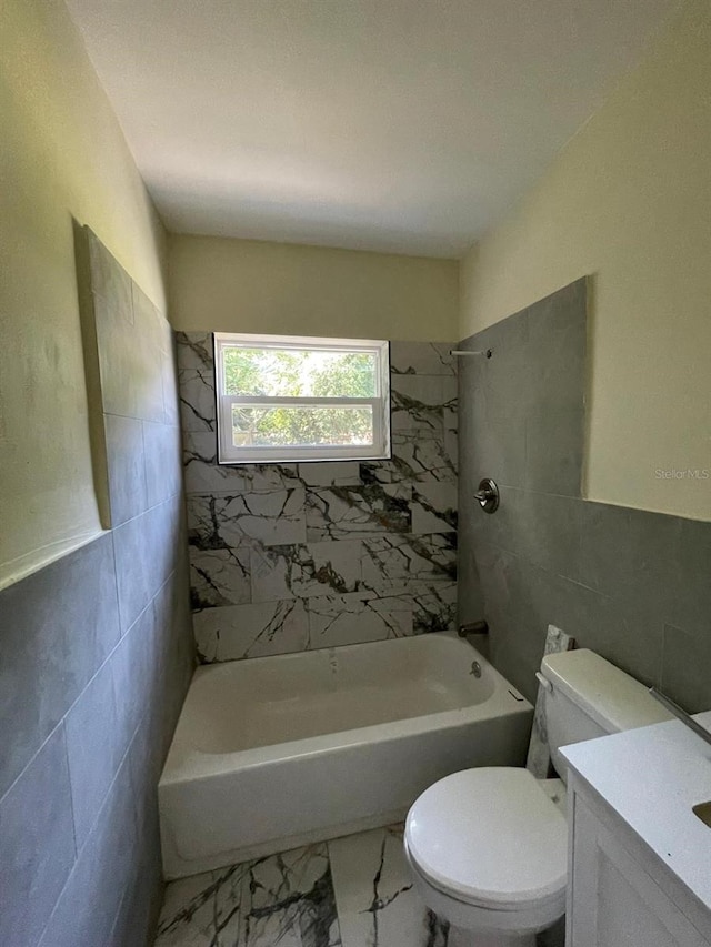 full bathroom featuring tile walls, toilet, tile floors, tiled shower / bath, and vanity