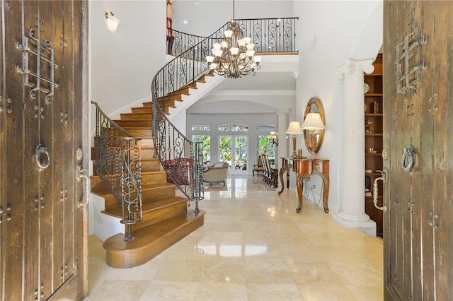 foyer featuring ornamental molding, a chandelier, a towering ceiling, and tile floors