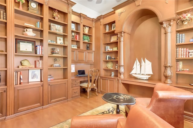 office area featuring built in desk, light hardwood / wood-style flooring, built in shelves, and ornate columns