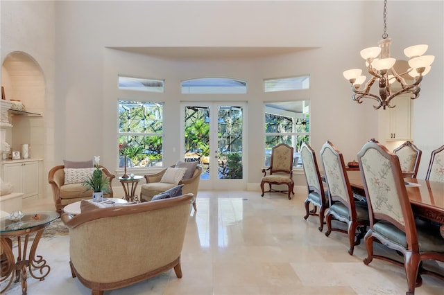 living room featuring french doors, light tile flooring, a towering ceiling, and an inviting chandelier