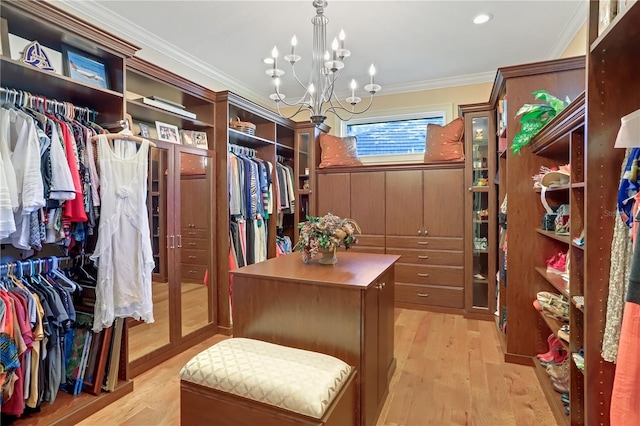 walk in closet featuring an inviting chandelier and light hardwood / wood-style floors