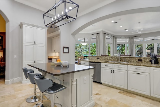 kitchen with white cabinets, sink, dishwasher, ceiling fan with notable chandelier, and decorative light fixtures