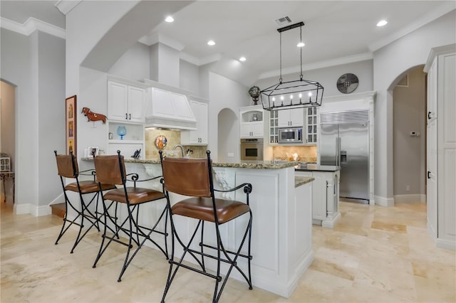 kitchen featuring tasteful backsplash, light tile floors, a breakfast bar area, and built in appliances