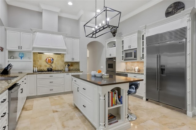 kitchen featuring white cabinetry, built in appliances, tasteful backsplash, and a kitchen island