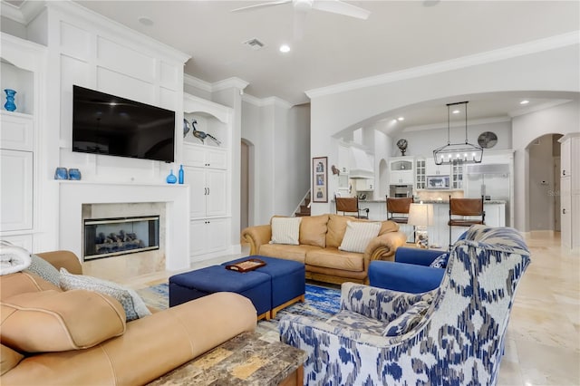 living room featuring built in features, ceiling fan, light tile flooring, a high end fireplace, and ornamental molding