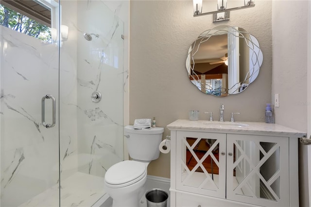 bathroom with walk in shower, ceiling fan, vanity, and toilet