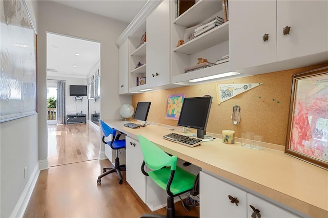 home office with built in desk, light hardwood / wood-style floors, and crown molding