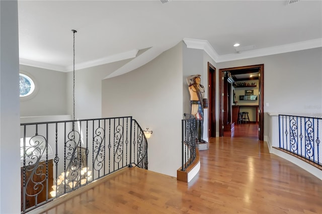 corridor featuring an inviting chandelier, hardwood / wood-style flooring, and ornamental molding