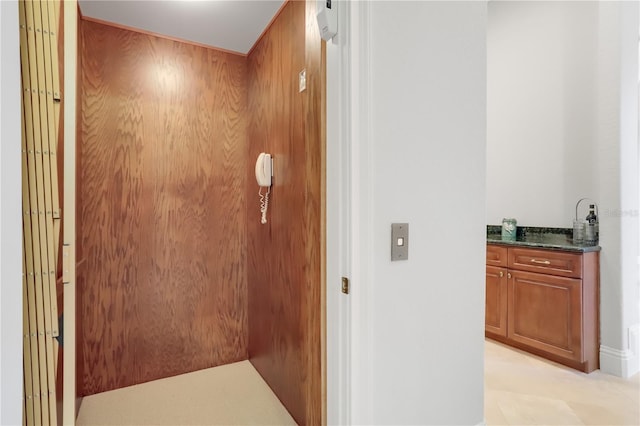 hall featuring wood walls and light tile floors