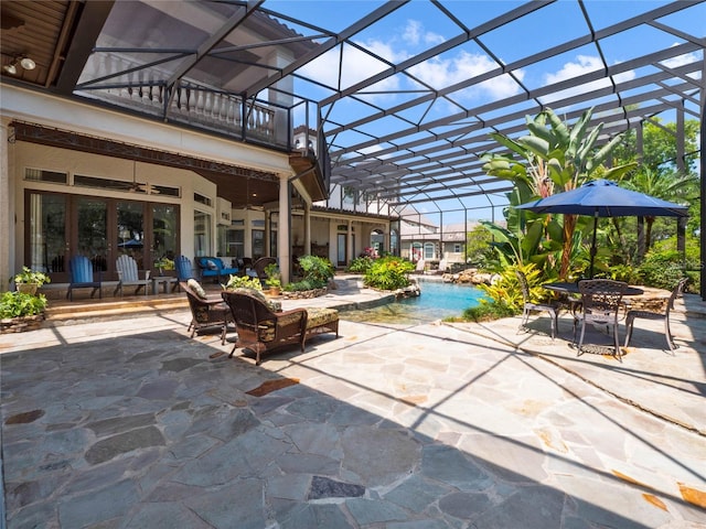 view of terrace with a balcony, glass enclosure, and ceiling fan