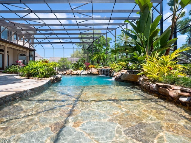 view of pool with pool water feature and glass enclosure