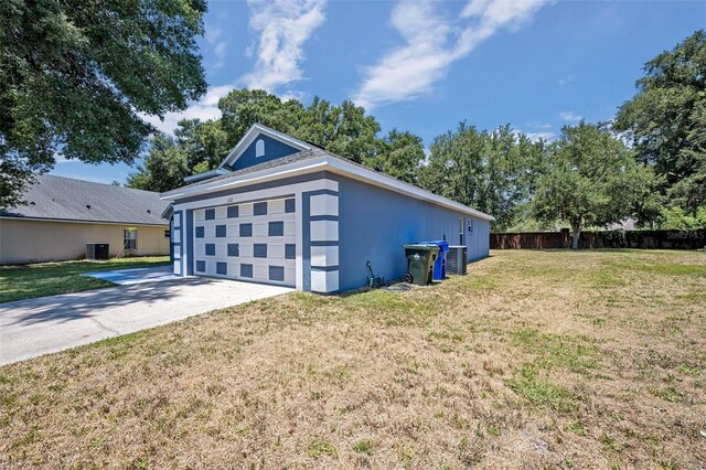 view of side of property with a lawn, a garage, and central AC