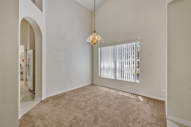 carpeted spare room featuring high vaulted ceiling