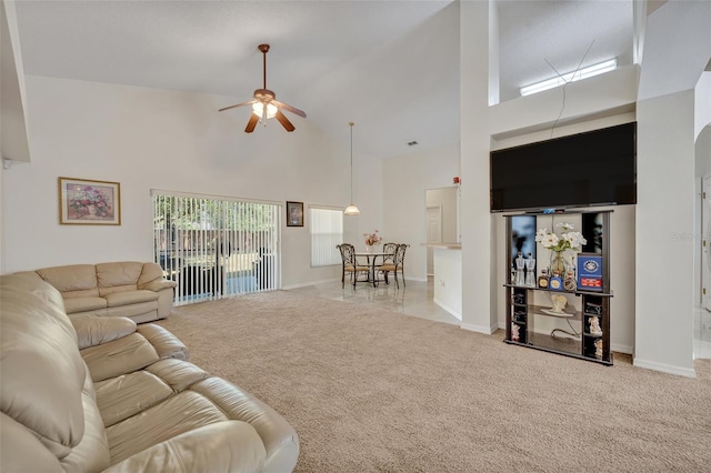 living room with ceiling fan, a high ceiling, and light colored carpet