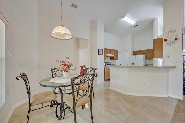 tiled dining room with a textured ceiling and high vaulted ceiling