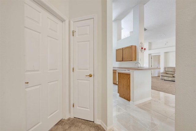 interior space featuring sink, kitchen peninsula, and light carpet