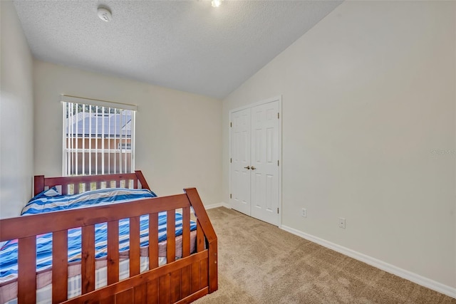 carpeted bedroom with a textured ceiling, a closet, and vaulted ceiling