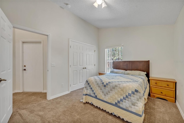 carpeted bedroom with a textured ceiling, a closet, and lofted ceiling