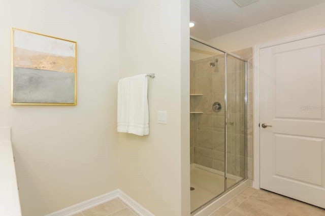 bathroom with a shower with shower door and tile floors