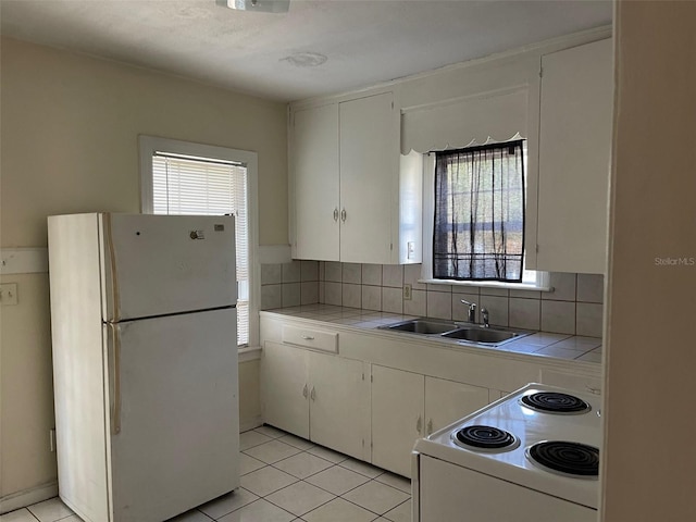 kitchen featuring white fridge, range, white cabinets, tile countertops, and sink