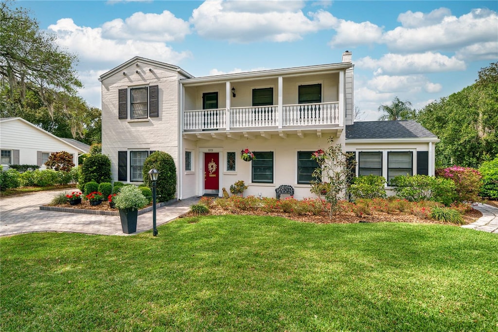 view of front of property featuring a front yard and a balcony