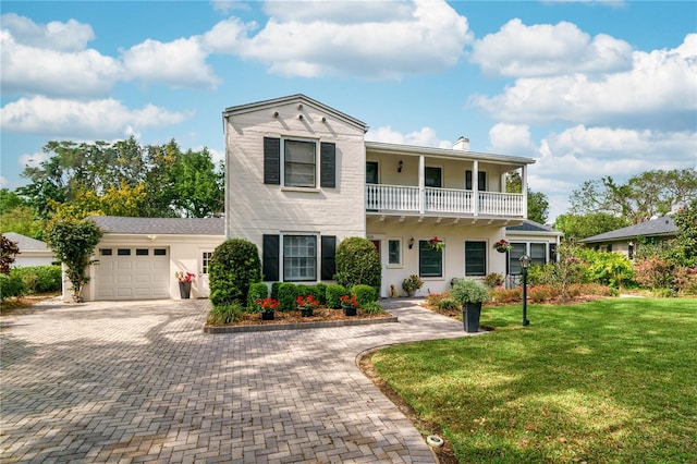 view of front of house featuring a balcony, a garage, and a front yard