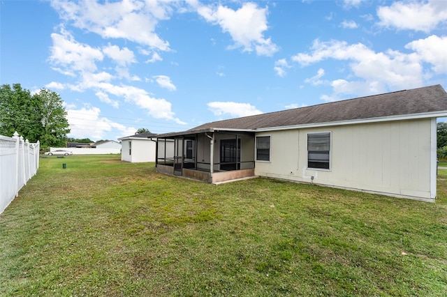 rear view of house featuring a sunroom and a lawn