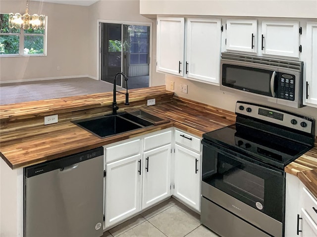 kitchen with appliances with stainless steel finishes, butcher block counters, hanging light fixtures, and sink