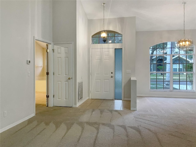 foyer featuring an inviting chandelier, light colored carpet, and a high ceiling