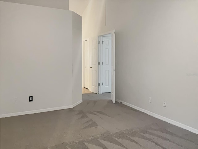 spare room featuring carpet flooring and a towering ceiling