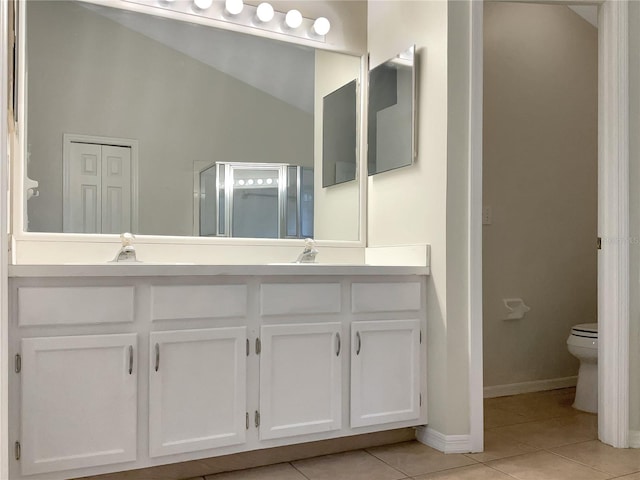 bathroom with double vanity, vaulted ceiling, toilet, and tile floors