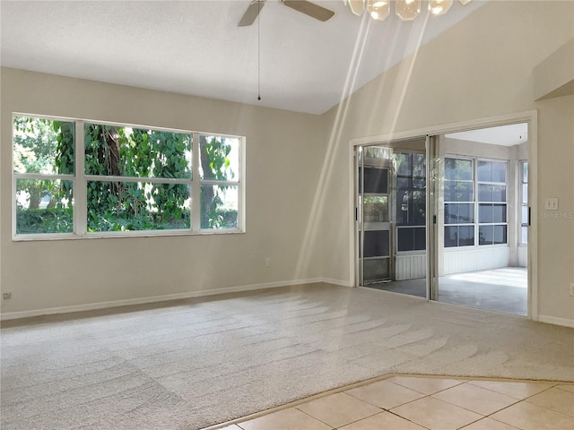 carpeted spare room with ceiling fan with notable chandelier and lofted ceiling