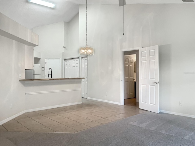 kitchen featuring carpet, white cabinets, high vaulted ceiling, an inviting chandelier, and kitchen peninsula